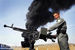 Афганский полицейский на фоне загоревшегося во время беспорядков нефтехранилища к западу от Кабула.