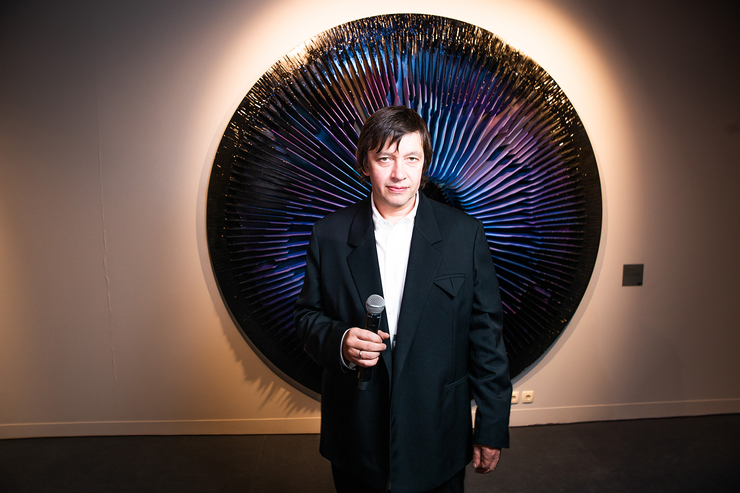 Автор выставки Василий Клюкин на фоне одной из своих работ